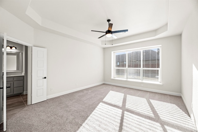 carpeted spare room featuring a raised ceiling and ceiling fan