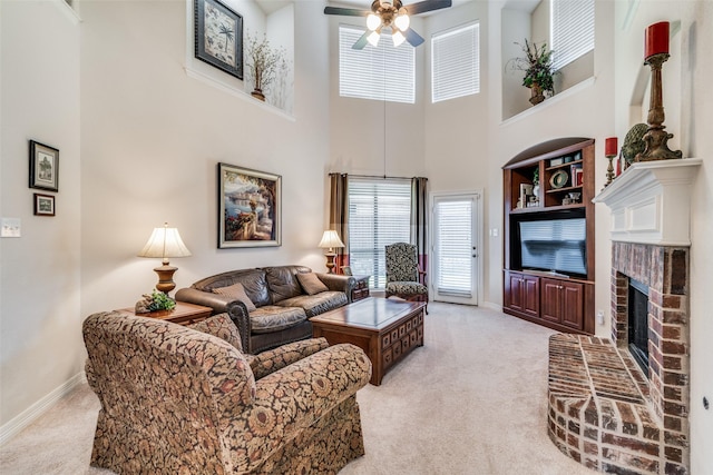 living room with light carpet, a towering ceiling, a fireplace, and ceiling fan