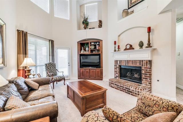 living room featuring a towering ceiling, a fireplace, and light colored carpet