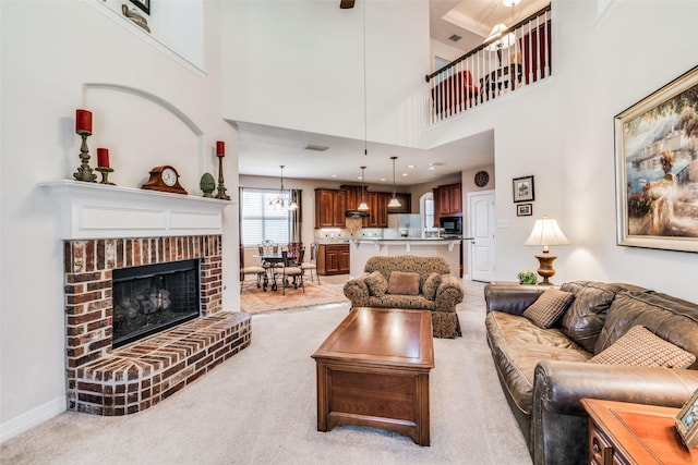 living room with light carpet, a brick fireplace, and a high ceiling