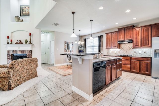 kitchen with appliances with stainless steel finishes, a breakfast bar, decorative backsplash, hanging light fixtures, and a kitchen island with sink