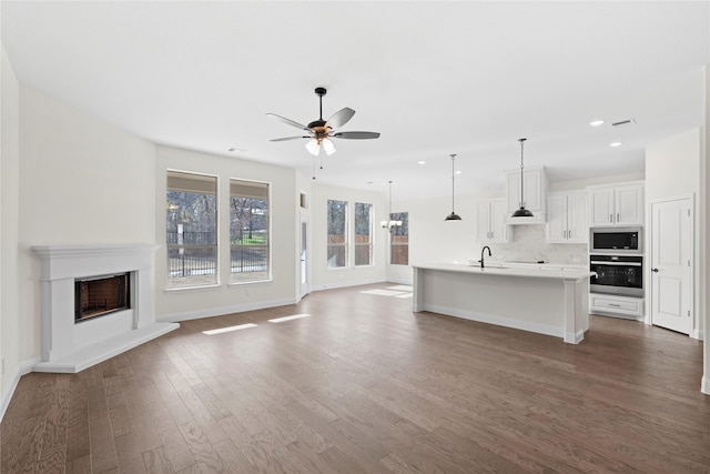 unfurnished living room featuring ceiling fan, sink, and dark hardwood / wood-style flooring