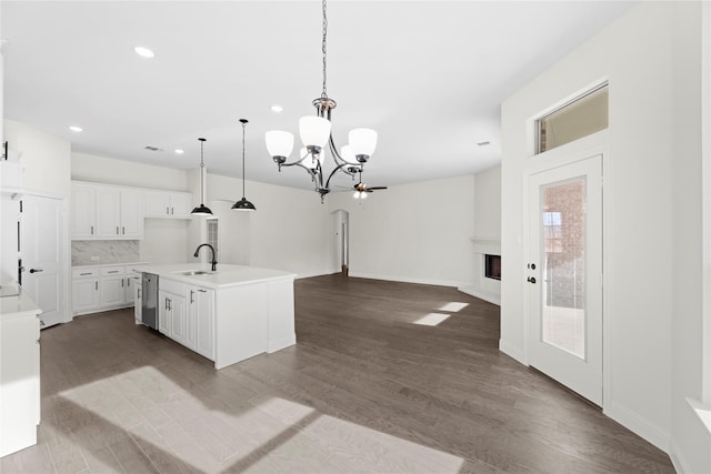 kitchen with sink, hardwood / wood-style flooring, hanging light fixtures, an island with sink, and white cabinets