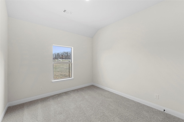 carpeted spare room with vaulted ceiling