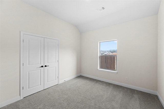 carpeted spare room featuring vaulted ceiling