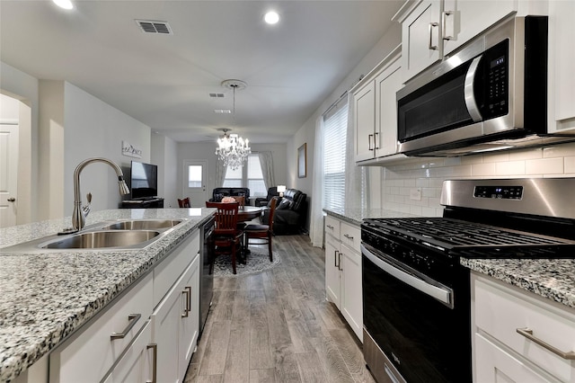 kitchen featuring visible vents, an inviting chandelier, light wood-style floors, stainless steel appliances, and a sink