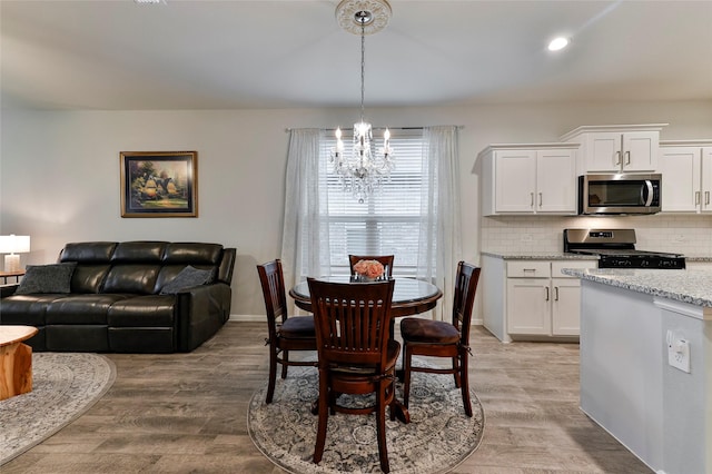 dining space featuring light wood finished floors, a chandelier, recessed lighting, and baseboards