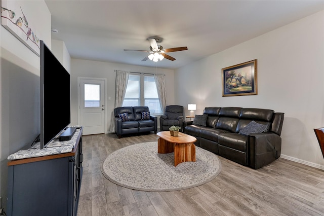 living area with baseboards, wood finished floors, and a ceiling fan