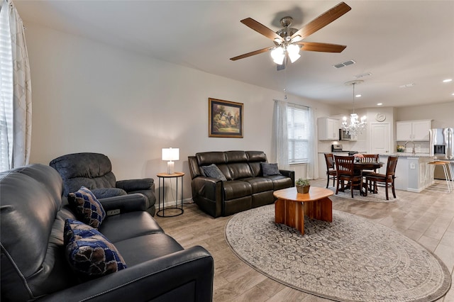 living room featuring sink, ceiling fan with notable chandelier, and light hardwood / wood-style flooring