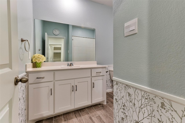 bathroom featuring wood finish floors, vanity, and a textured wall