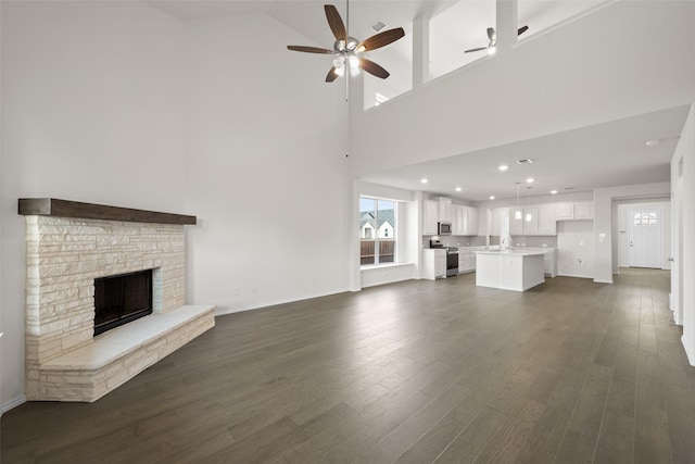 371 Freestall Dr, Midlothian, TX 76065 - unfurnished living room featuring ceiling fan, a towering ceiling, dark wood finished floors, a fireplace, and baseboards