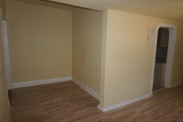 unfurnished room with hardwood / wood-style flooring, electric panel, and a textured ceiling