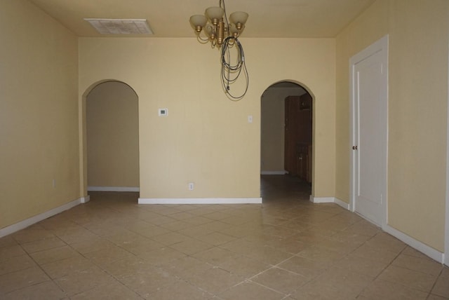 tiled spare room with a notable chandelier