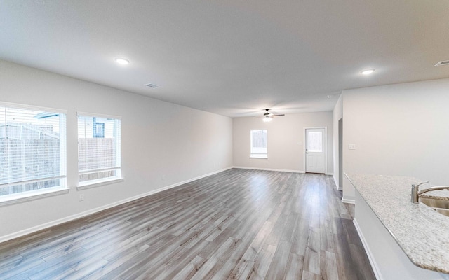 unfurnished living room with a sink, baseboards, and wood finished floors