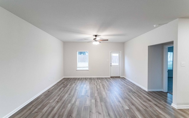 empty room with light wood-style floors, ceiling fan, and baseboards