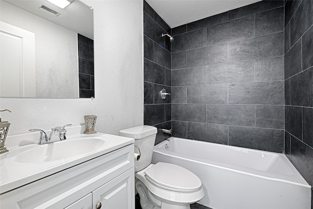 full bathroom with tiled shower / bath, vanity, toilet, and a textured ceiling