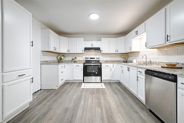 kitchen with sink, appliances with stainless steel finishes, white cabinetry, light stone countertops, and light hardwood / wood-style floors