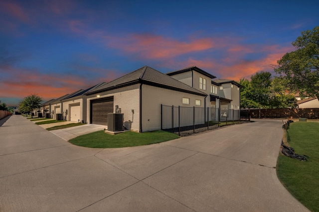 property exterior at dusk featuring central AC, a garage, and a yard