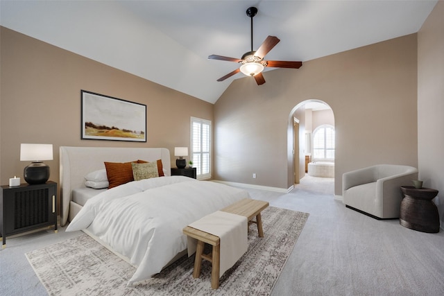 bedroom with light carpet, multiple windows, arched walkways, and lofted ceiling