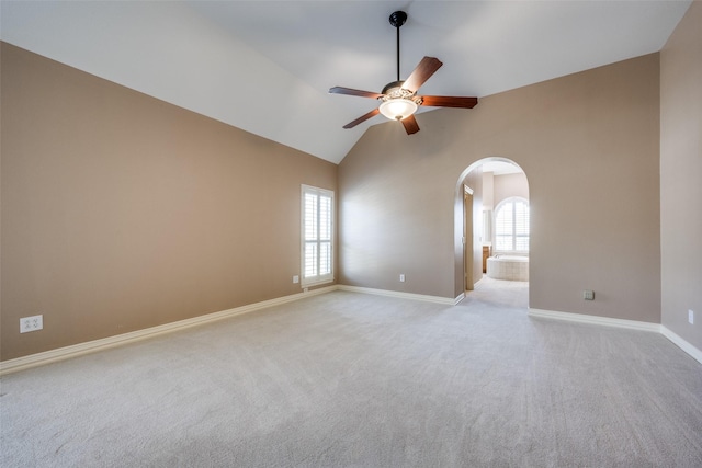 spare room with arched walkways, plenty of natural light, and light carpet