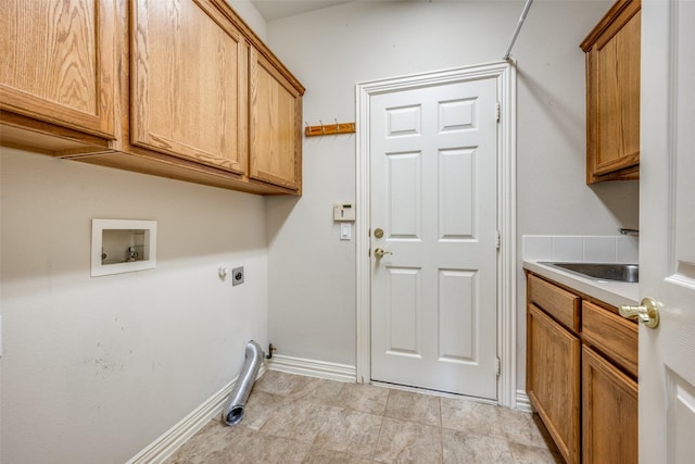 clothes washing area with hookup for an electric dryer, washer hookup, a sink, baseboards, and cabinet space