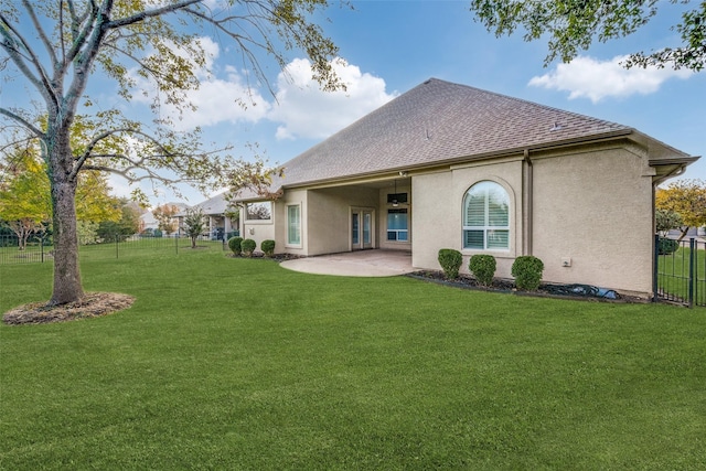 rear view of house featuring stucco siding, a patio area, fence, and a lawn