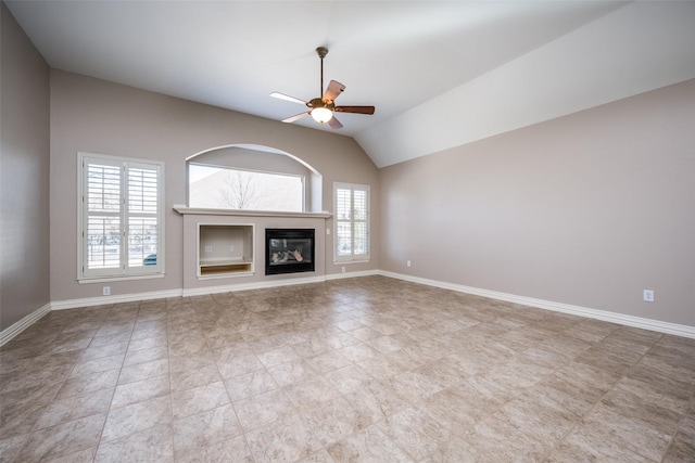 unfurnished living room featuring ceiling fan, a glass covered fireplace, lofted ceiling, and baseboards