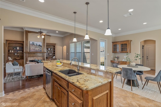 kitchen with decorative light fixtures, dishwasher, an island with sink, sink, and ornamental molding