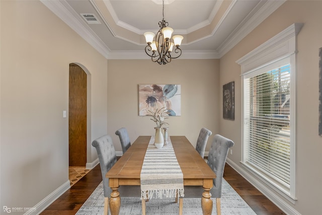 dining space featuring a notable chandelier, dark wood-type flooring, ornamental molding, and a raised ceiling