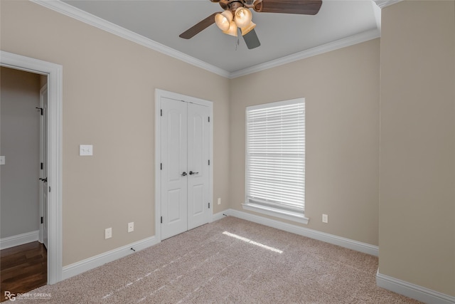 unfurnished bedroom with crown molding, ceiling fan, carpet flooring, and a closet