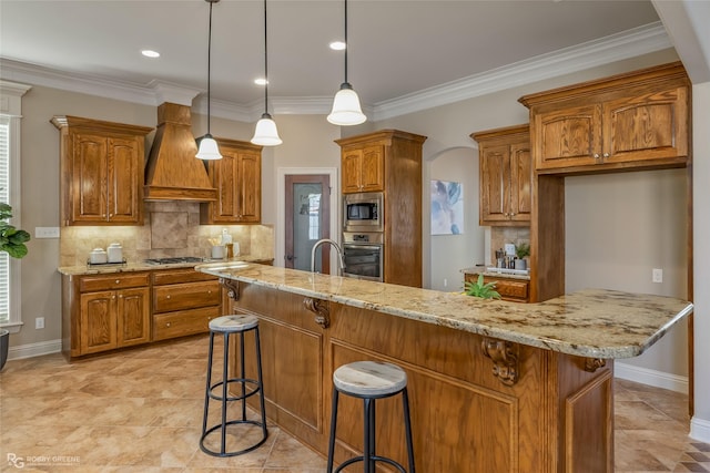 kitchen featuring custom exhaust hood, appliances with stainless steel finishes, a breakfast bar, and a center island with sink