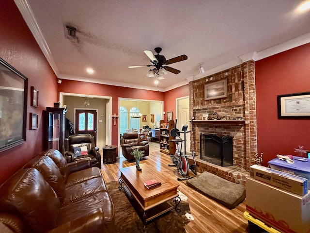 living room with hardwood / wood-style flooring, ornamental molding, a brick fireplace, and ceiling fan