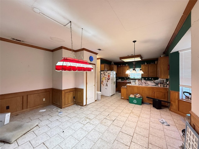 kitchen with white fridge with ice dispenser, brown cabinetry, wainscoting, and visible vents