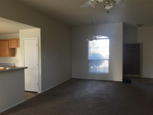 unfurnished dining area featuring dark colored carpet and ceiling fan with notable chandelier