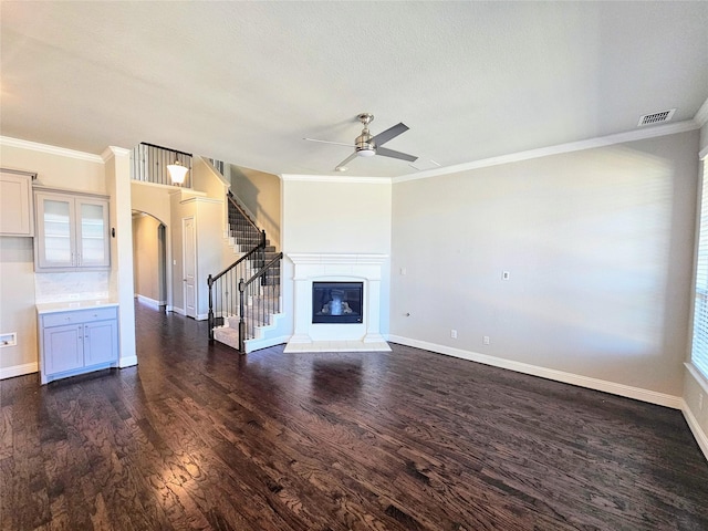 unfurnished living room featuring dark hardwood / wood-style flooring, ornamental molding, and ceiling fan