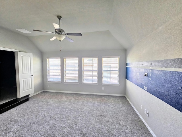 carpeted empty room with ceiling fan, vaulted ceiling, and a textured ceiling