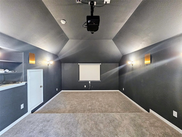 carpeted home theater with vaulted ceiling