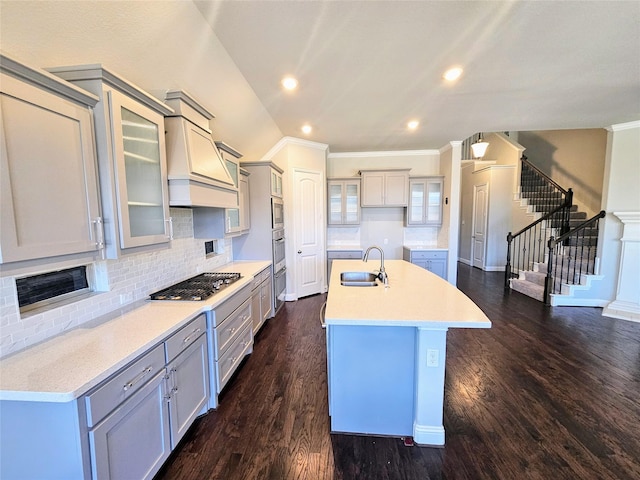 kitchen featuring appliances with stainless steel finishes, tasteful backsplash, an island with sink, sink, and dark hardwood / wood-style flooring