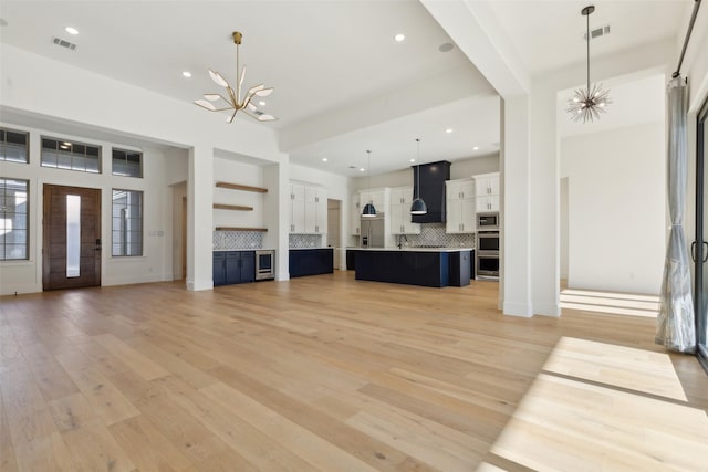 unfurnished living room with light hardwood / wood-style floors and a chandelier