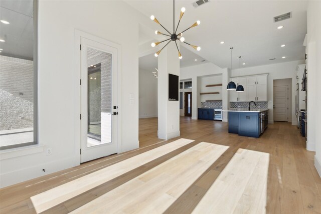 kitchen with decorative light fixtures, a breakfast bar area, decorative backsplash, a kitchen island with sink, and blue cabinetry