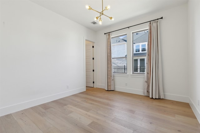 unfurnished room with light hardwood / wood-style flooring and a notable chandelier