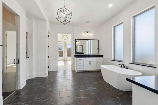 bathroom featuring an inviting chandelier, vanity, plus walk in shower, and a healthy amount of sunlight