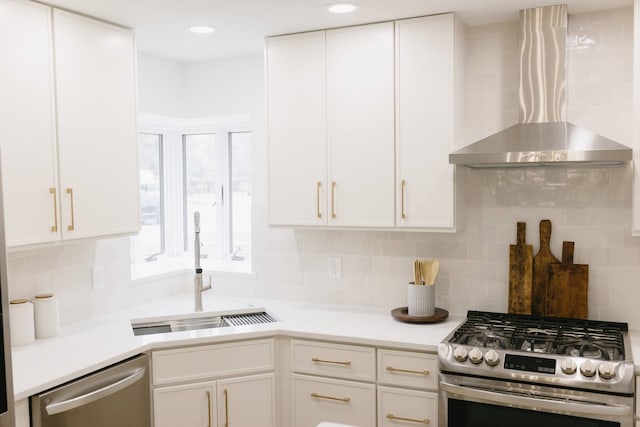 kitchen featuring tasteful backsplash, wall chimney range hood, stainless steel appliances, and white cabinets