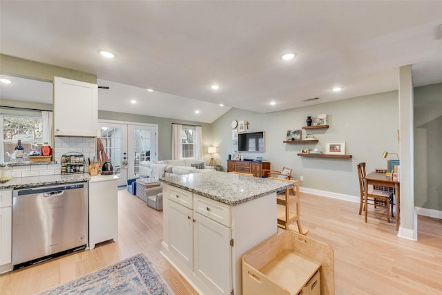 kitchen featuring a kitchen island, dishwasher, white cabinets, a kitchen breakfast bar, and french doors