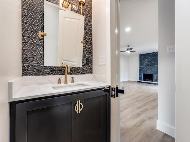 bathroom featuring a premium fireplace, vanity, hardwood / wood-style floors, and ceiling fan