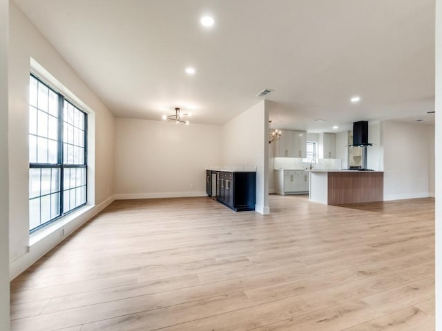 unfurnished living room with a notable chandelier and light hardwood / wood-style floors