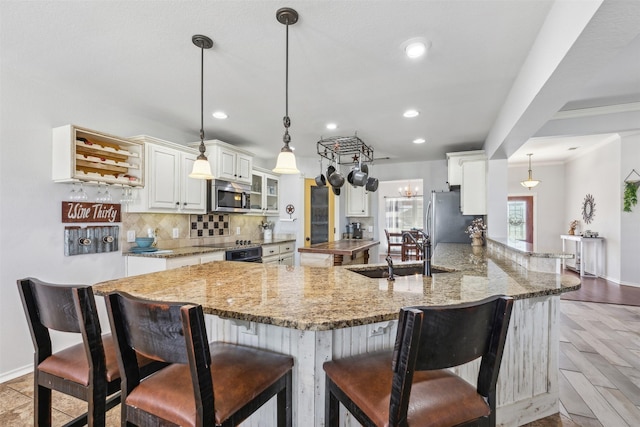 kitchen featuring sink, hanging light fixtures, kitchen peninsula, stainless steel appliances, and light stone countertops