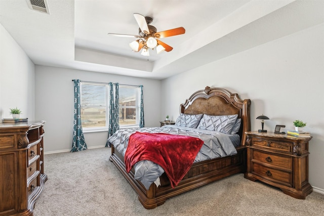 bedroom with ceiling fan, a raised ceiling, and light carpet