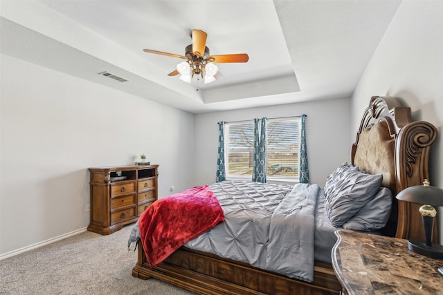 bedroom with ceiling fan, carpet flooring, and a raised ceiling