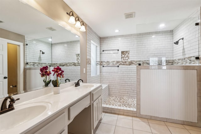 bathroom with tiled shower, vanity, and tile patterned flooring